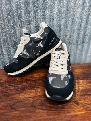 Black and white sneakers with patterned sole on a wooden surface