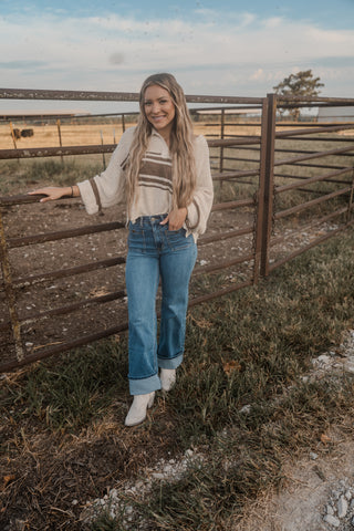Woman standing by a wooden fence in a rural setting