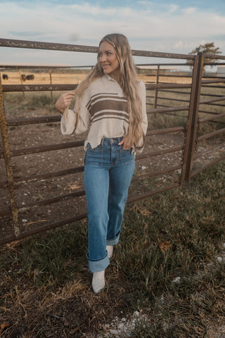 Woman standing by a wooden fence in an open field