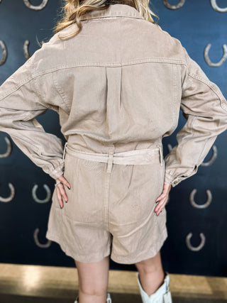 Person wearing a beige jumpsuit with a blue background