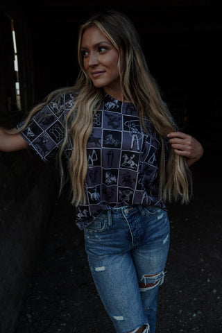 Woman wearing a patterned shirt and jeans in a dark setting