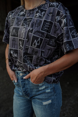 Person wearing a patterned shirt and jeans against a dark background