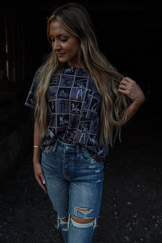 Woman wearing a patterned shirt and ripped jeans against a dark background