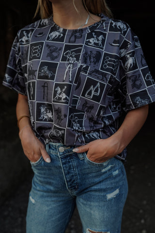 Person wearing a patterned shirt and jeans against a dark background