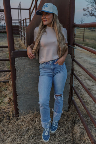 Woman in casual outfit standing near a metal gate in an outdoor setting