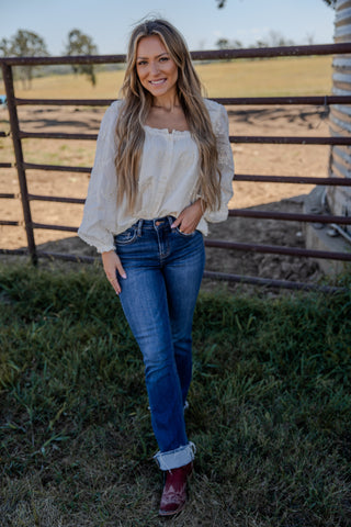 Woman standing in a field with a wooden fence and grass in the background