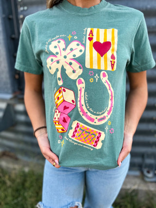 Person wearing a green t-shirt with colorful graphic designs outdoors.