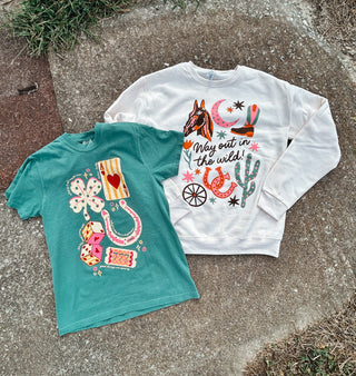Teal t-shirt and white sweatshirt with colorful designs on a concrete surface.