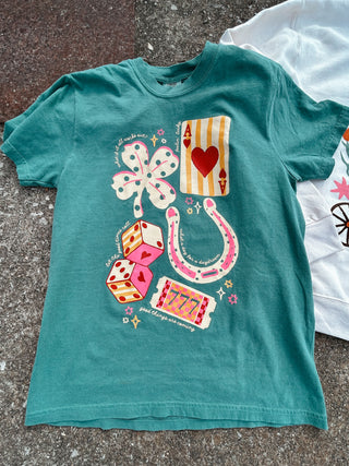 Teal t-shirt with colorful graphic design on a textured surface