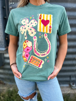 Person wearing a teal t-shirt with colorful graphic designs against a metal wall background