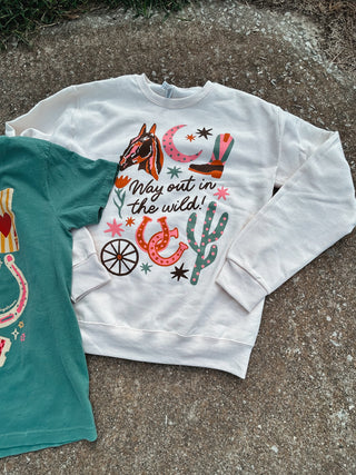 White sweatshirt with cowboy-themed graphics on a concrete surface