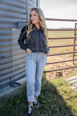 Woman standing outdoors near a metal building with a field in the background