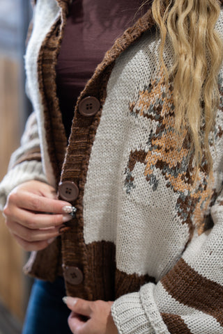 Close-up of a person wearing a patterned cardigan with brown buttons.