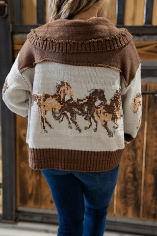 Person wearing a sweater with horse design in front of wooden doors