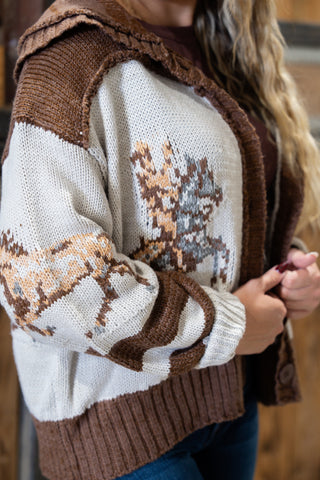 Person wearing a sweater with deer pattern and brown vest