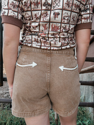 Person wearing a patterned shirt and brown shorts with white accents.