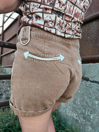 Person wearing brown shorts with a patterned top in an outdoor setting