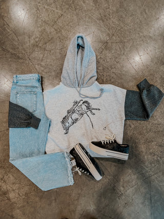 Hoodie with graphic design, jeans, and sneakers on a concrete floor