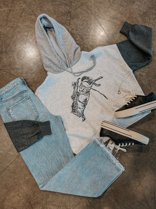 Hoodie with graphic design, jeans, and sneakers on a textured surface