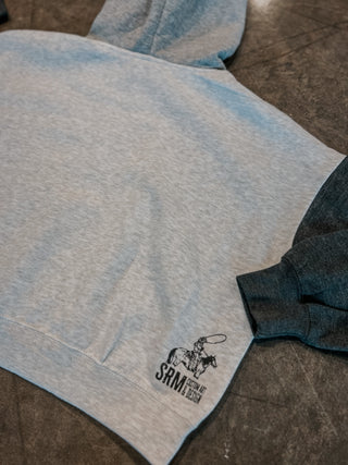 Gray hoodie with a logo on the sleeve, laid flat on a surface.
