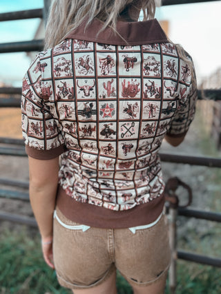 Person wearing a patterned shirt and shorts standing in front of a metal gate.