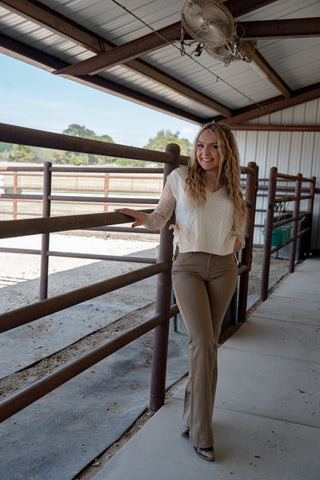 Woman standing in a barn or stable area with wooden stalls.