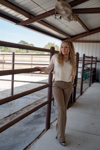 Woman standing in a barn or stable area with wooden stalls.