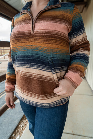 Person wearing a colorful striped sweater with a blurred background