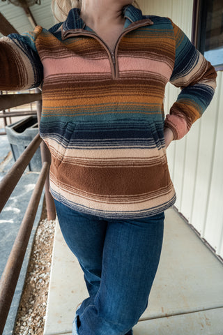 Person wearing a striped sweater and blue jeans on a porch