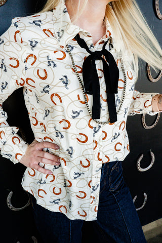 Person wearing a white shirt with horse shoe pattern and black bow tie.