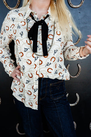 Person wearing a patterned blouse with a black bow tie against a dark background