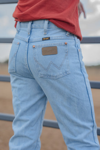 Light blue jeans with a brand logo on the pocket against a blurred background