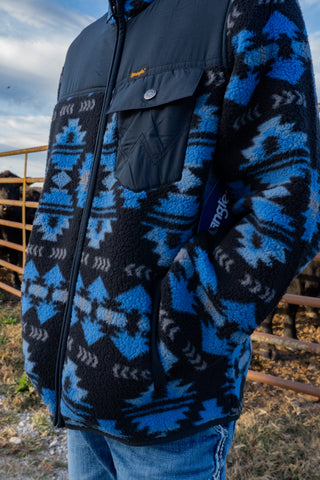 Person wearing a blue and black patterned jacket with a blurred background