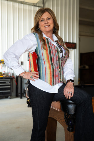 Woman wearing a colorful striped vest in an indoor setting