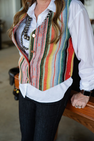 Person wearing a colorful striped vest over a white shirt with a blurred background