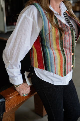 Person wearing a colorful striped vest over a white shirt with a blurred background