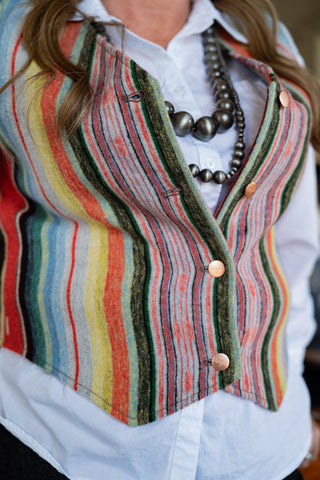 Colorful striped vest over a white shirt with a necklace.
