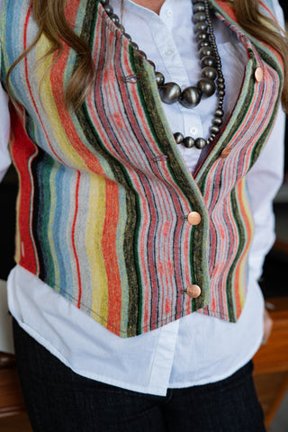 Person wearing a colorful striped vest over a white shirt.