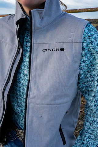 Person wearing a gray vest with 'CINCH' branding outdoors.